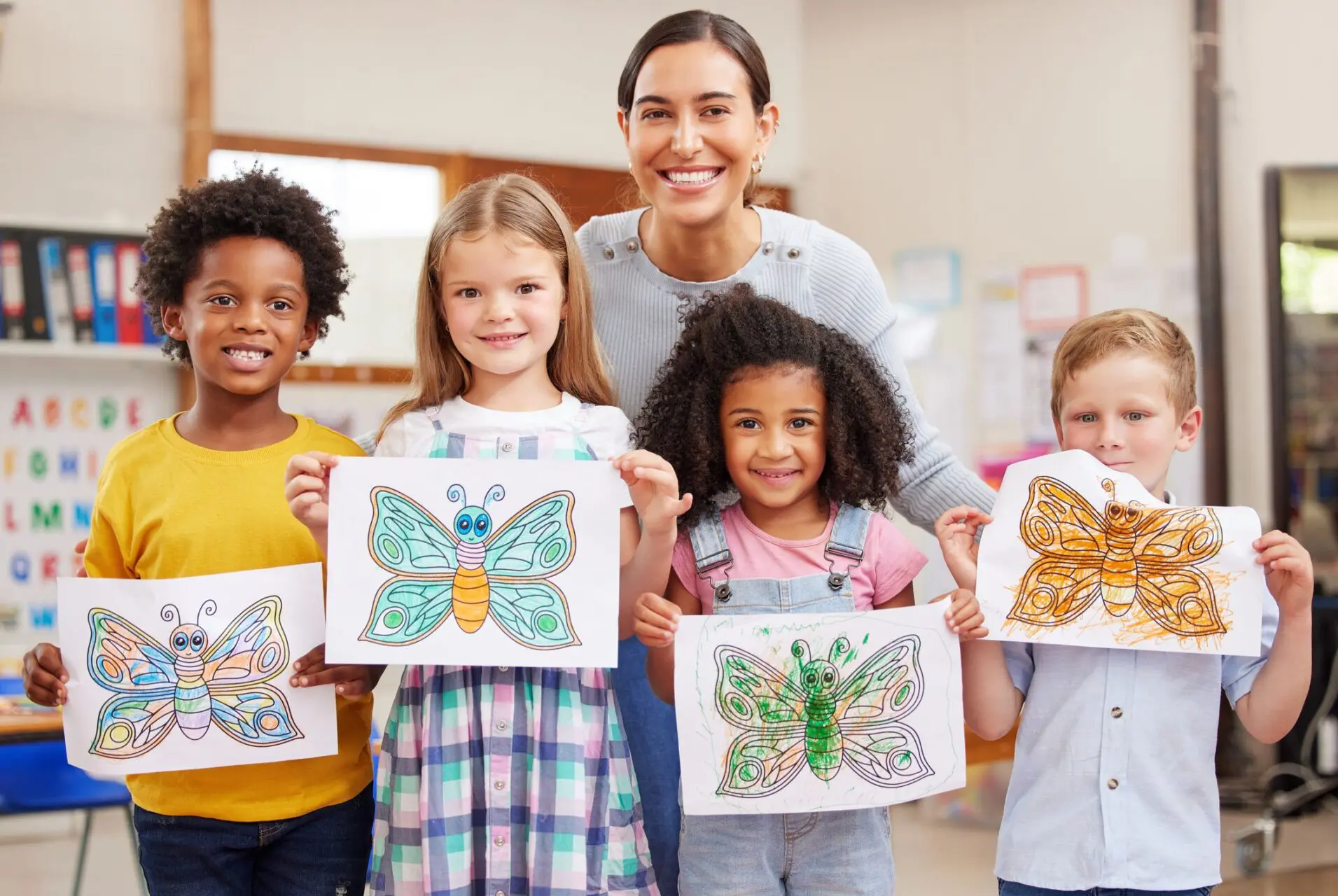 Children proudly display colorful butterfly drawings with a smiling adult behind them.