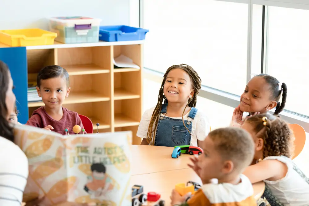 Children sitting around a table, listening to a story.